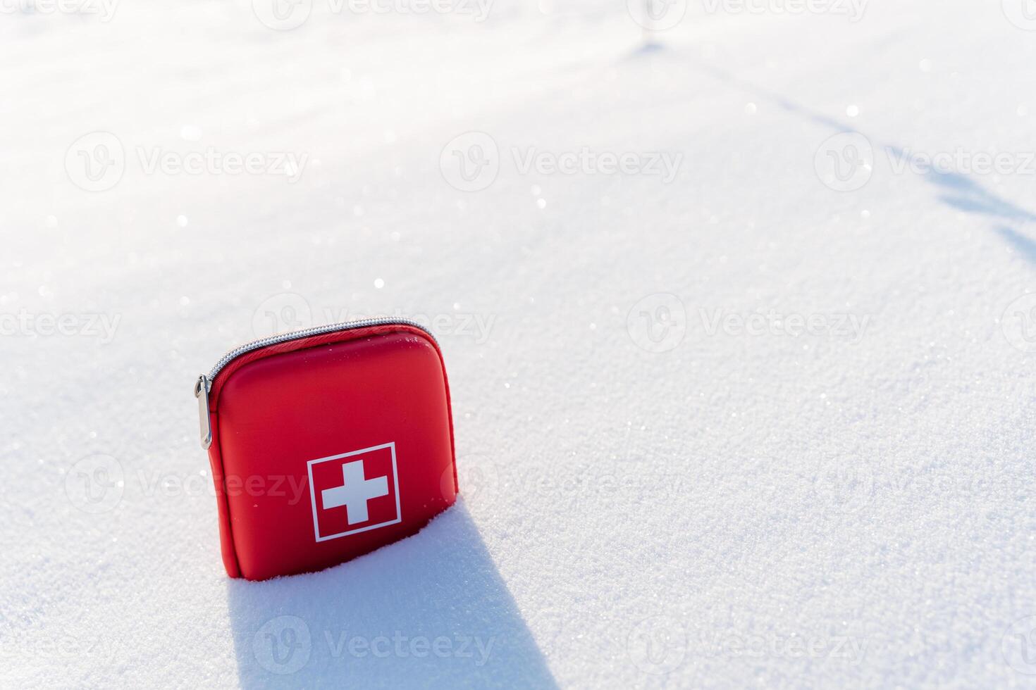 A red first aid kit laying in the snow photo