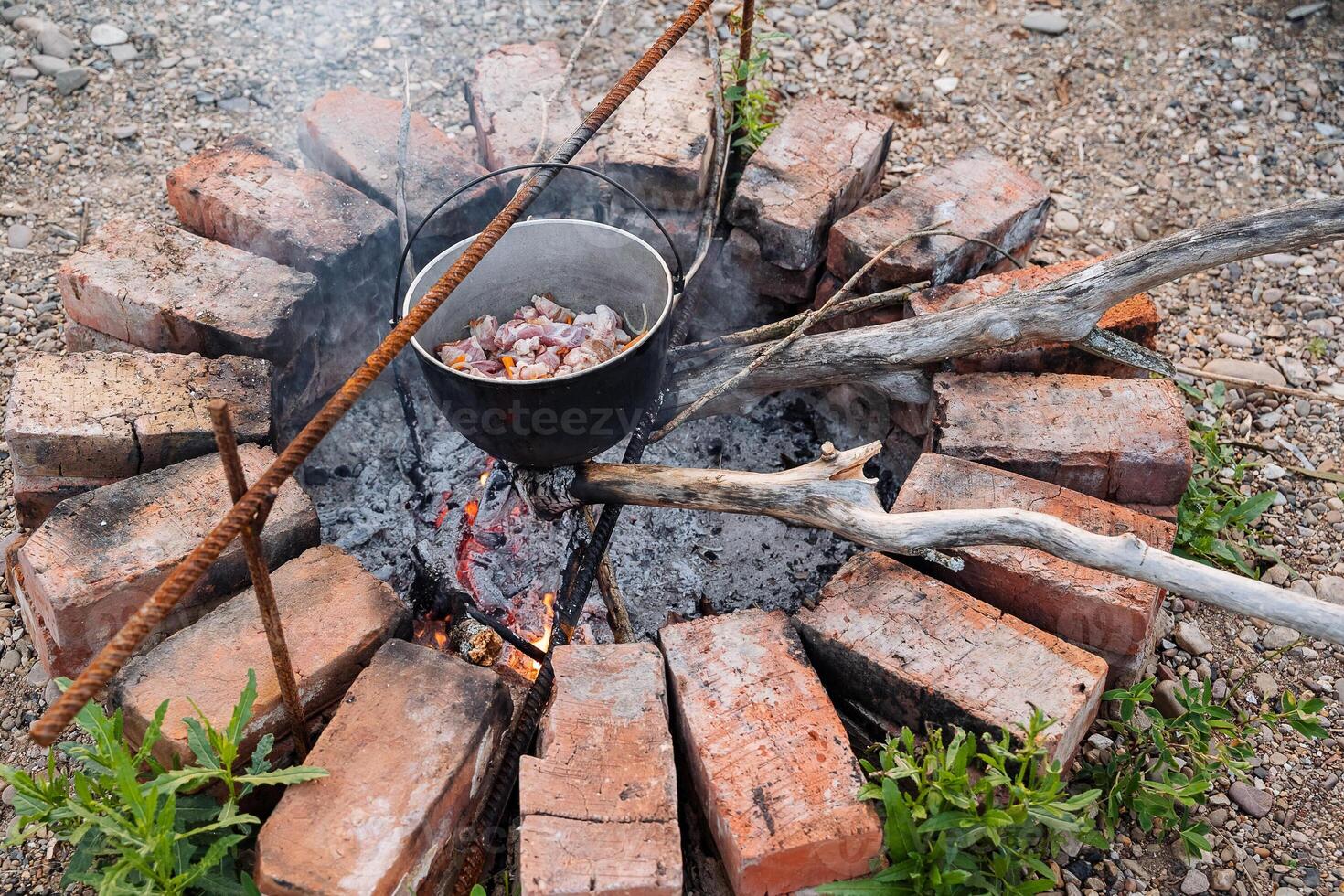 A pot of food cooking on an open fire photo