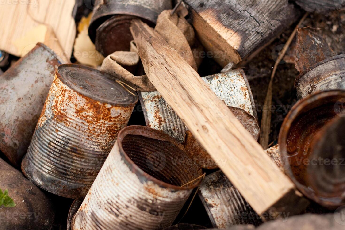 Old rusty cans and wood are piled together photo