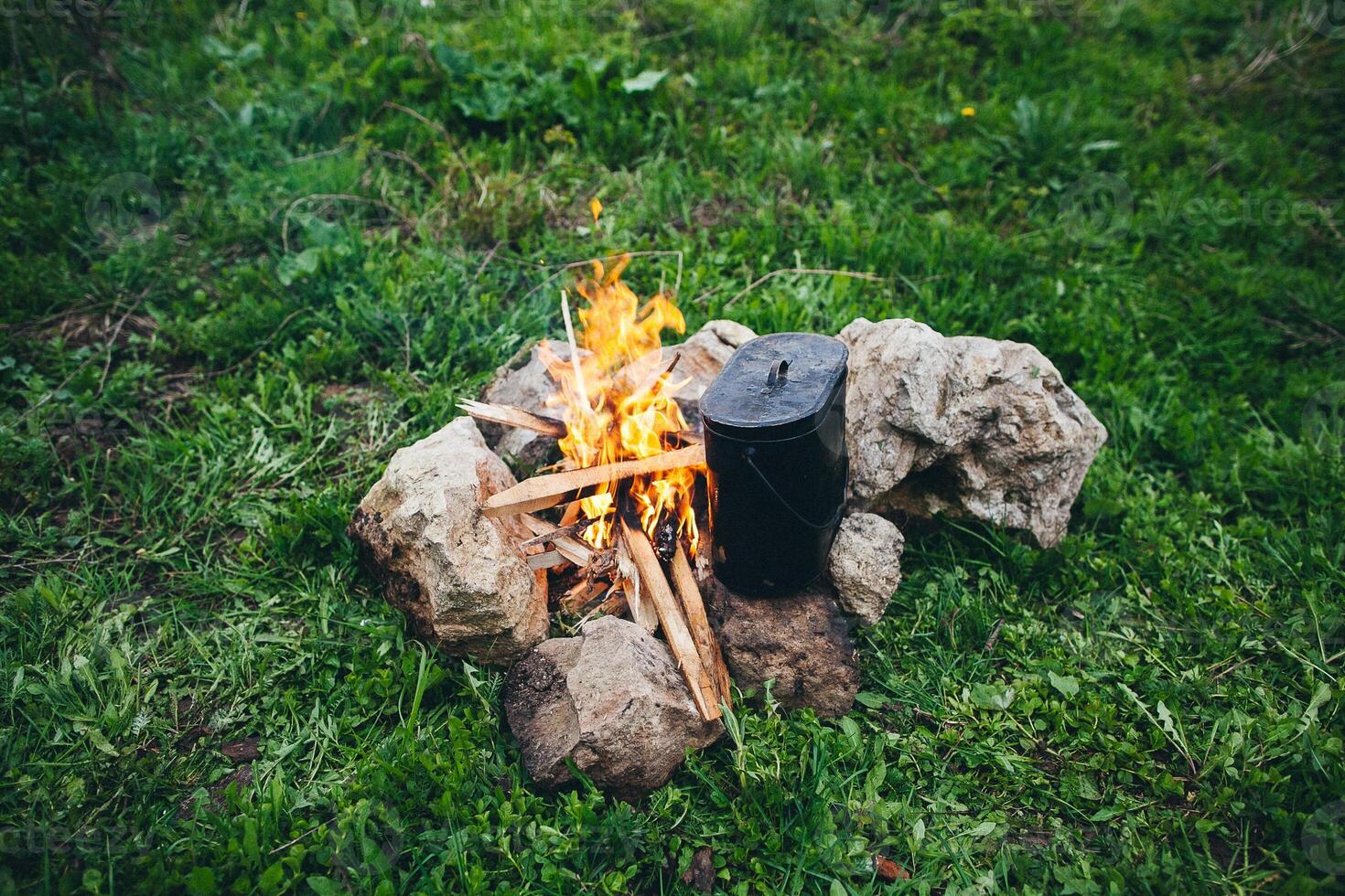 A campfire with a cup of coffee on the ground photo
