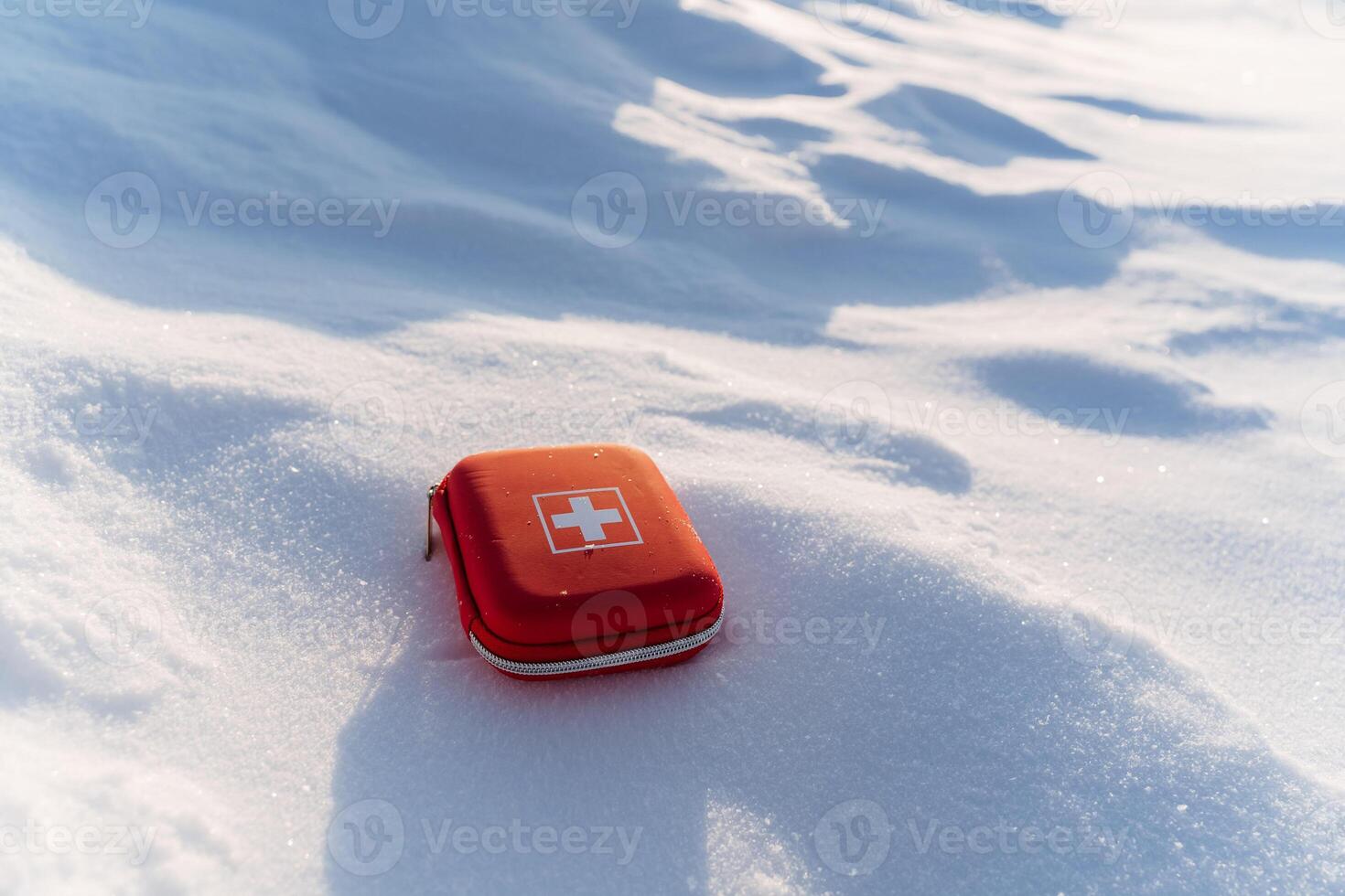 A red first aid kit laying in the snow photo