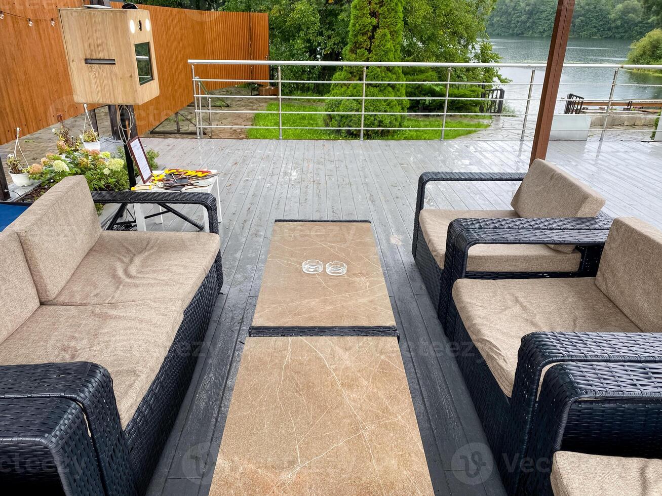 A deck with furniture and a table in front of a lake photo
