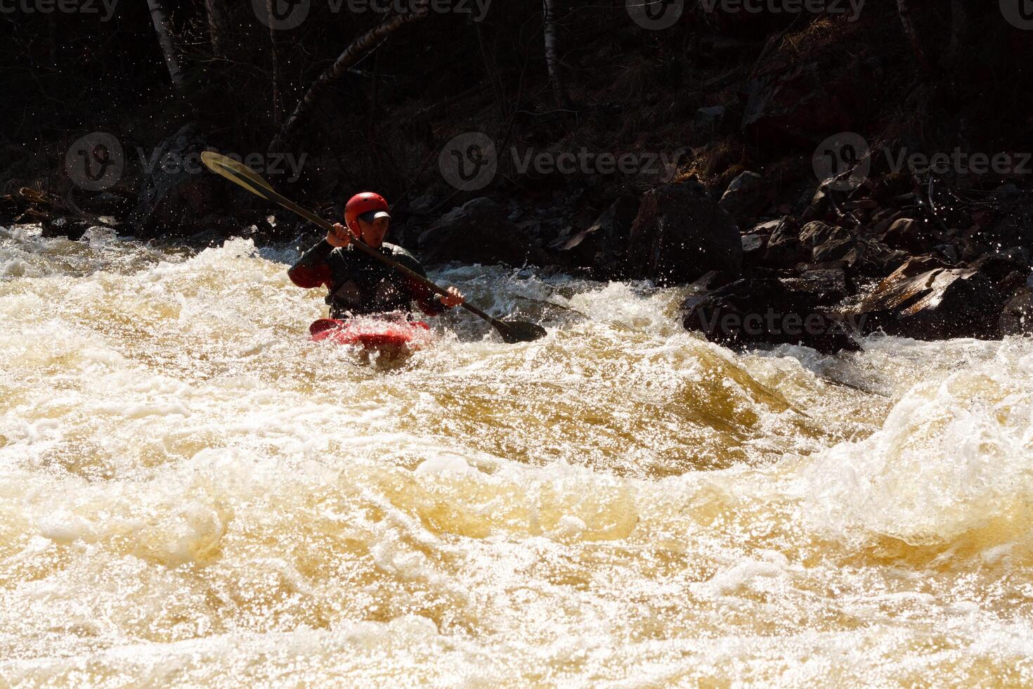 A man in a kayak paddling through a rapid river photo