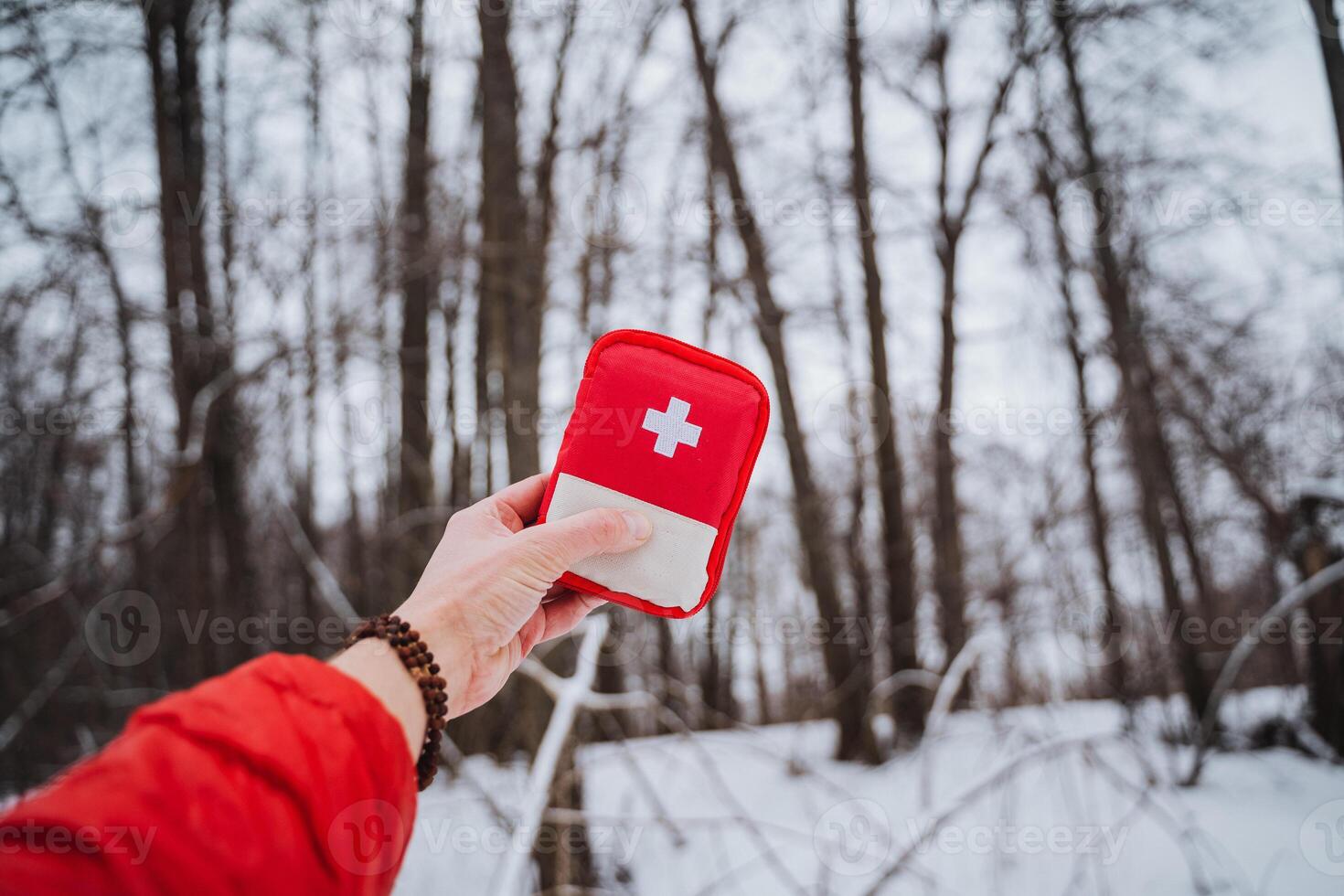 A person holding a red first aid kit in the snow photo