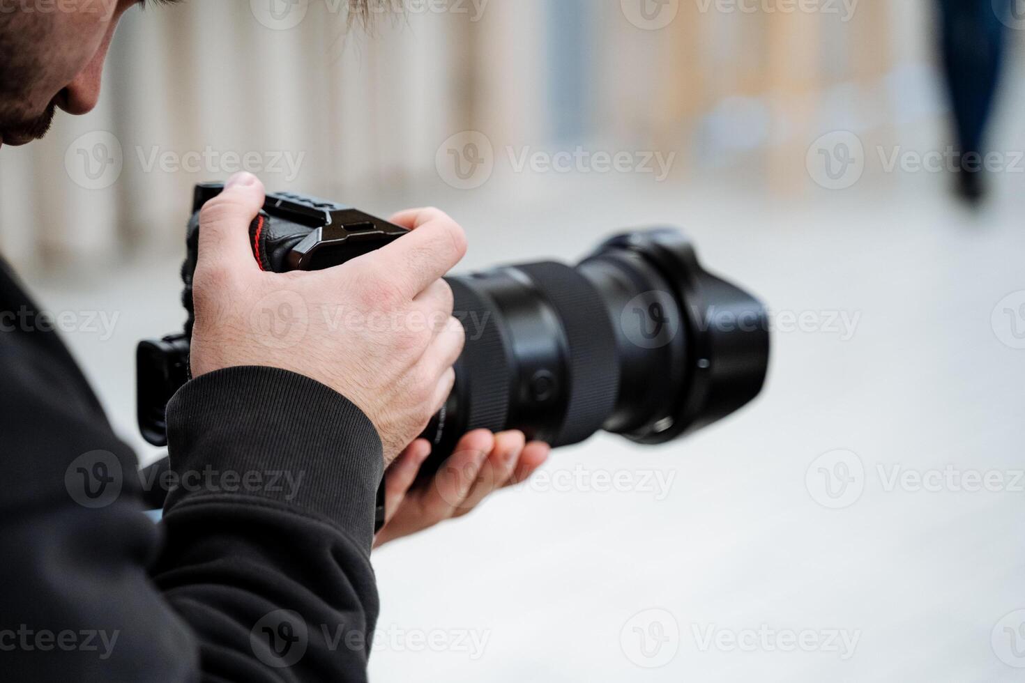 A man holding a camera while standing in front of a white wall photo
