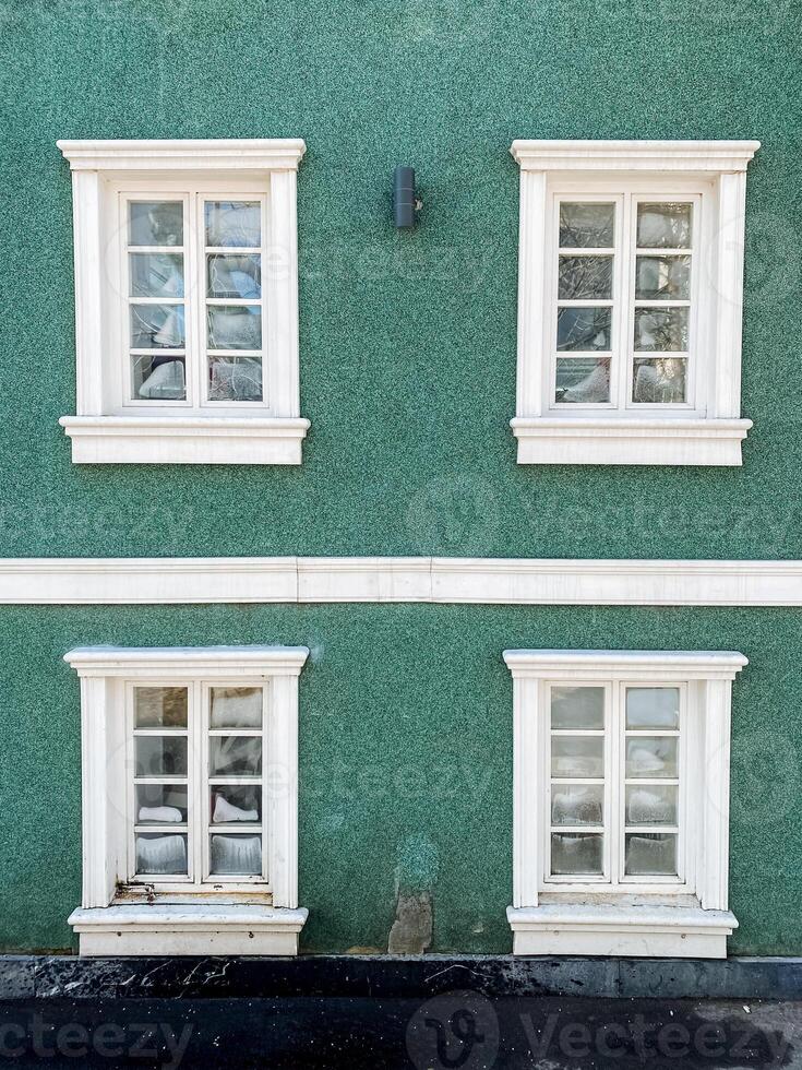Three windows on a green building with white trim photo