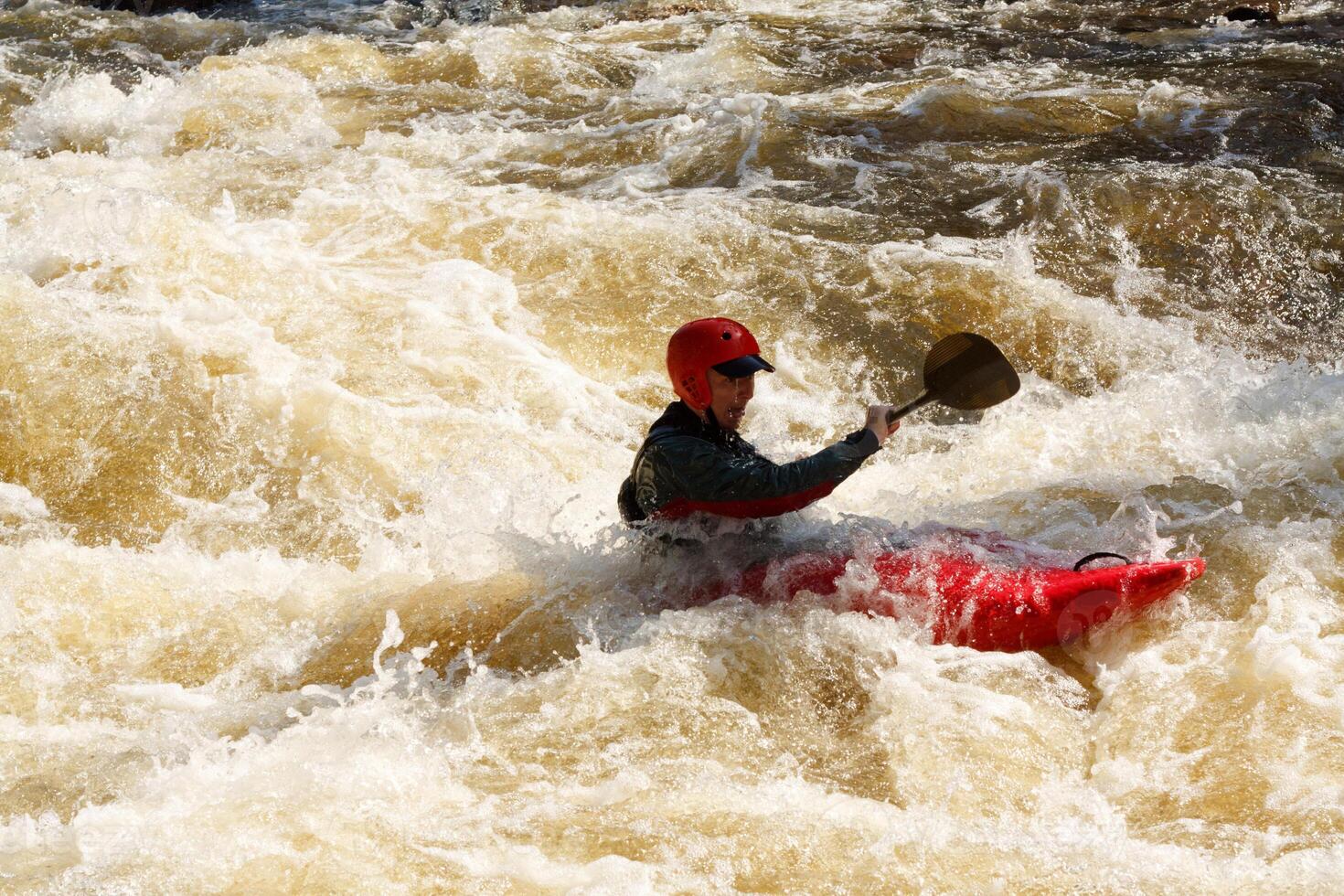 A man in a kayak paddling through a river photo