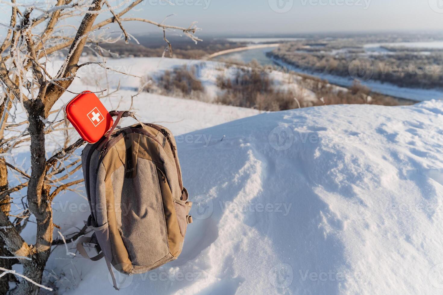 A backpack with an emergency first aid kit on top of a snowy hill photo