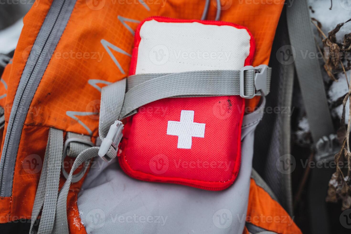 A red first aid kit on the back of a backpack photo
