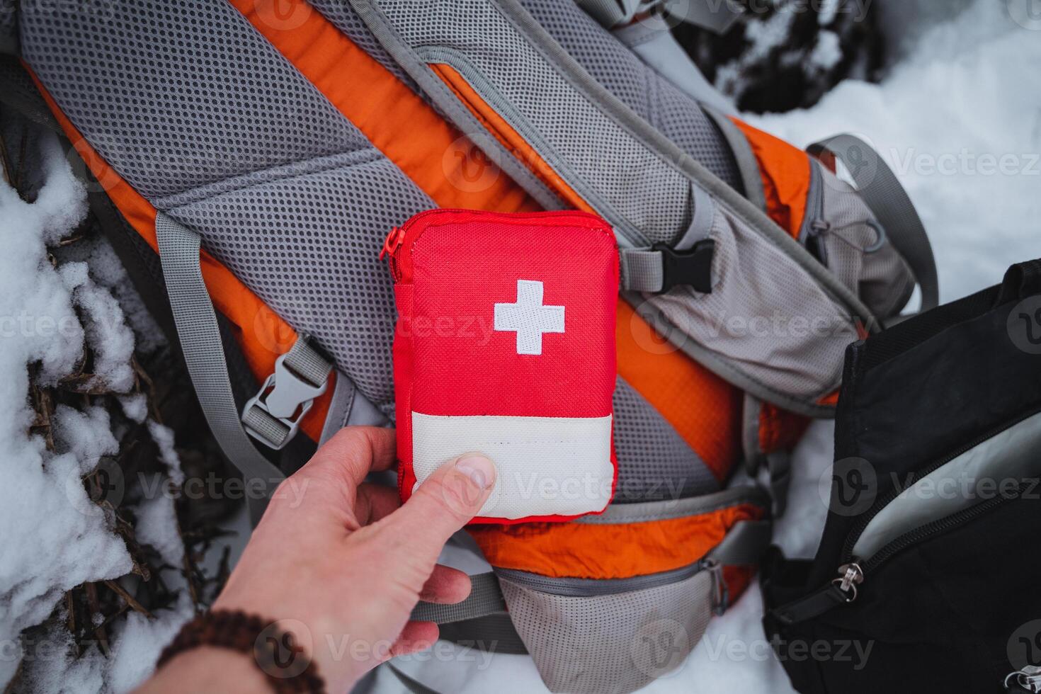 A person holding a red first aid kit in the snow photo