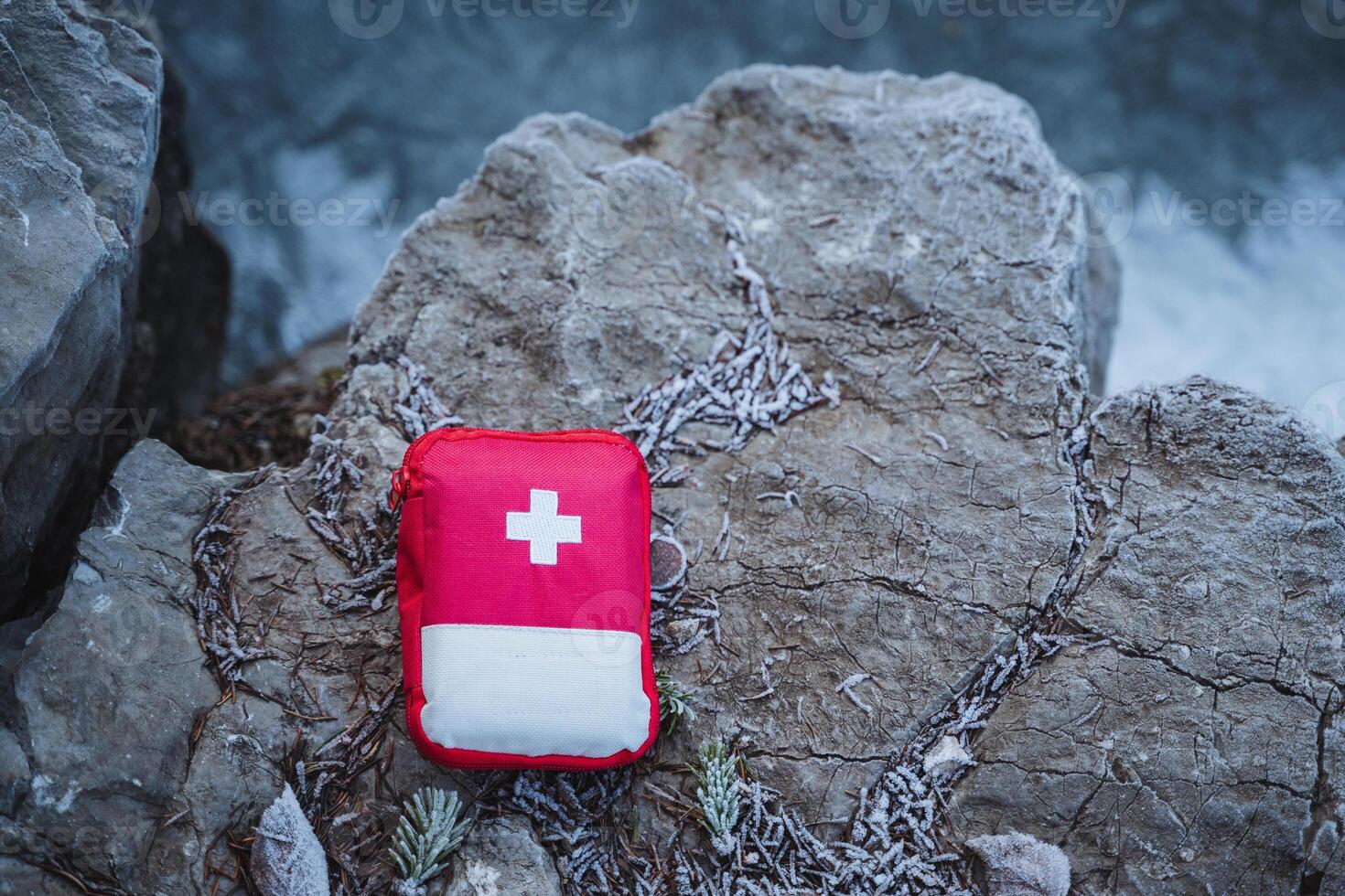 A red first aid kit laying on the rocks photo