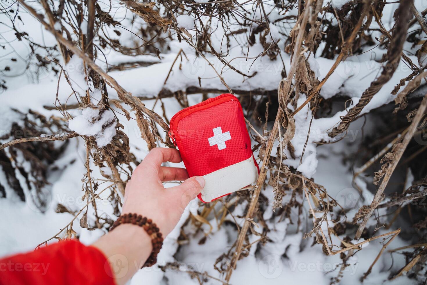 A person holding a red first aid kit in the snow photo