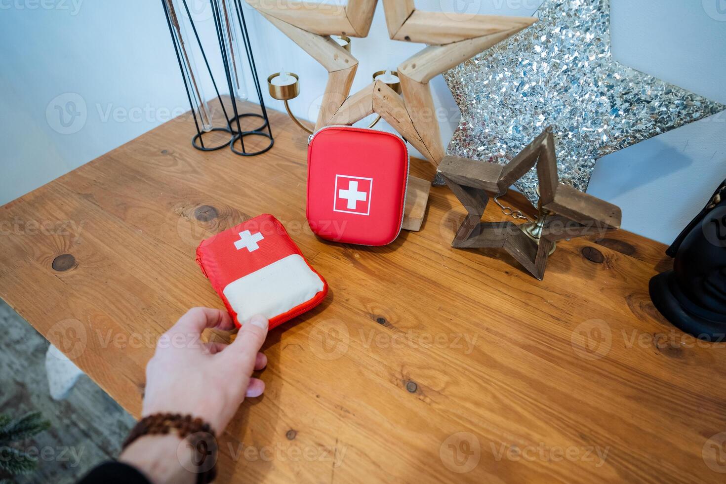 A person holding a red first aid kit on a table photo