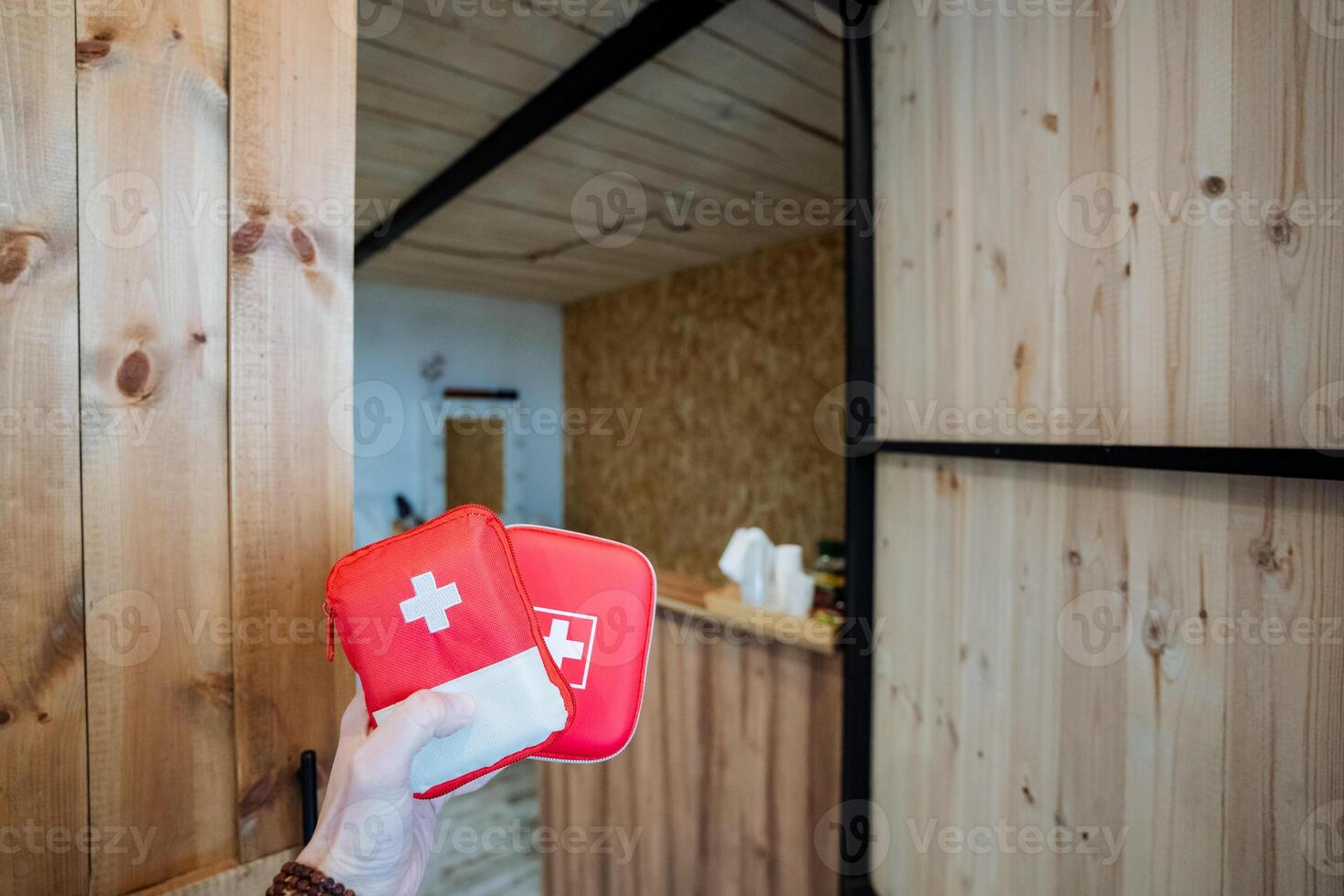 A person holding a first aid kit in front of a wooden door photo