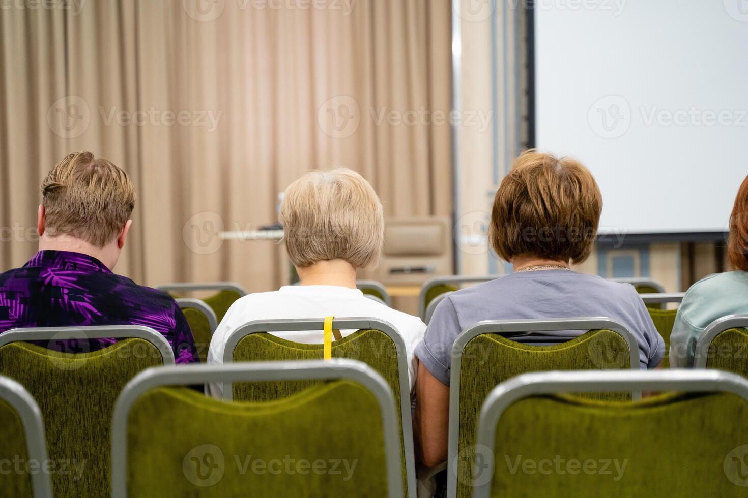 Back view of people sitting in chairs in a conference room photo
