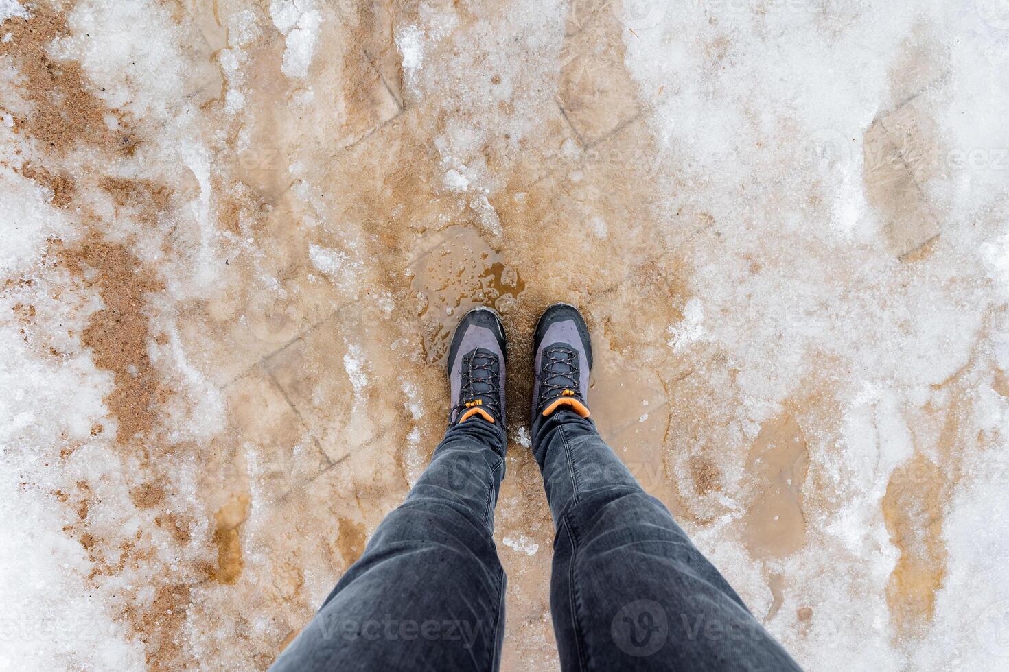 A person standing on a snowy surface with their feet in the air photo