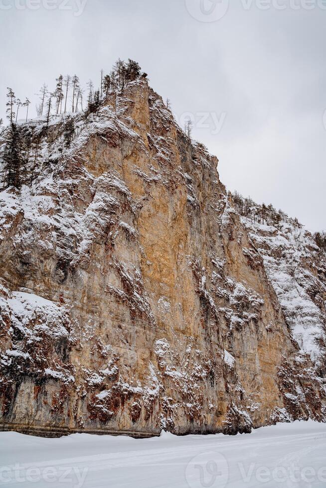 A snowy mountain side with a cliff photo