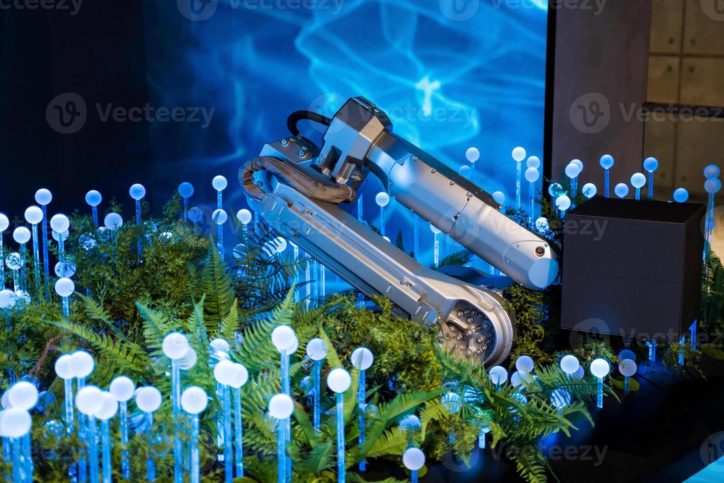 A robot is sitting on a table with plants and lights photo