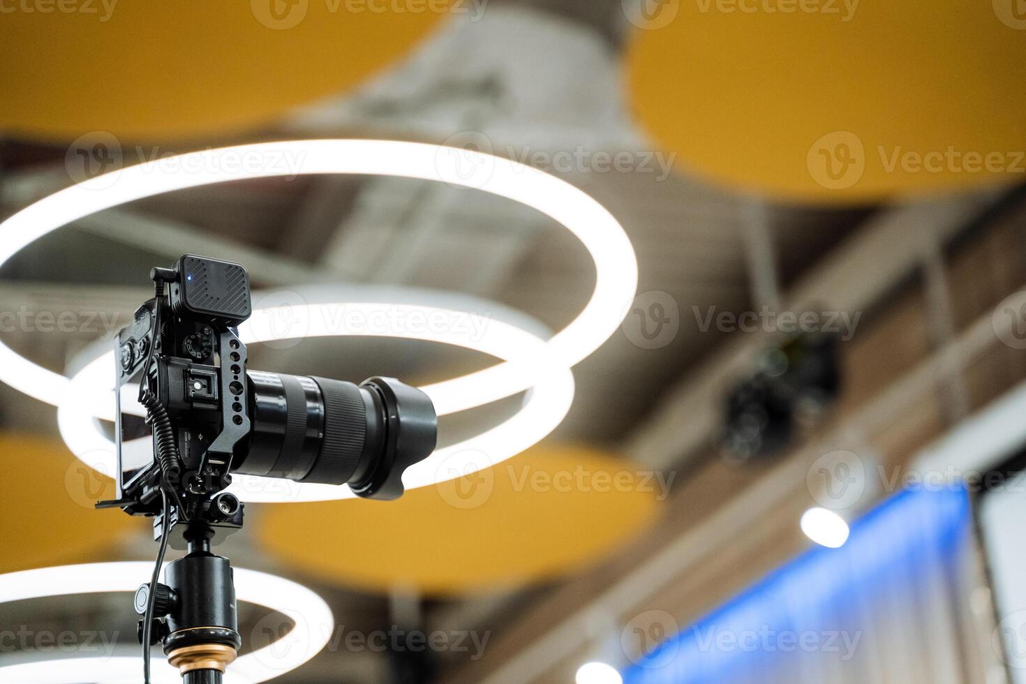 A camera on a tripod in front of a circular light photo