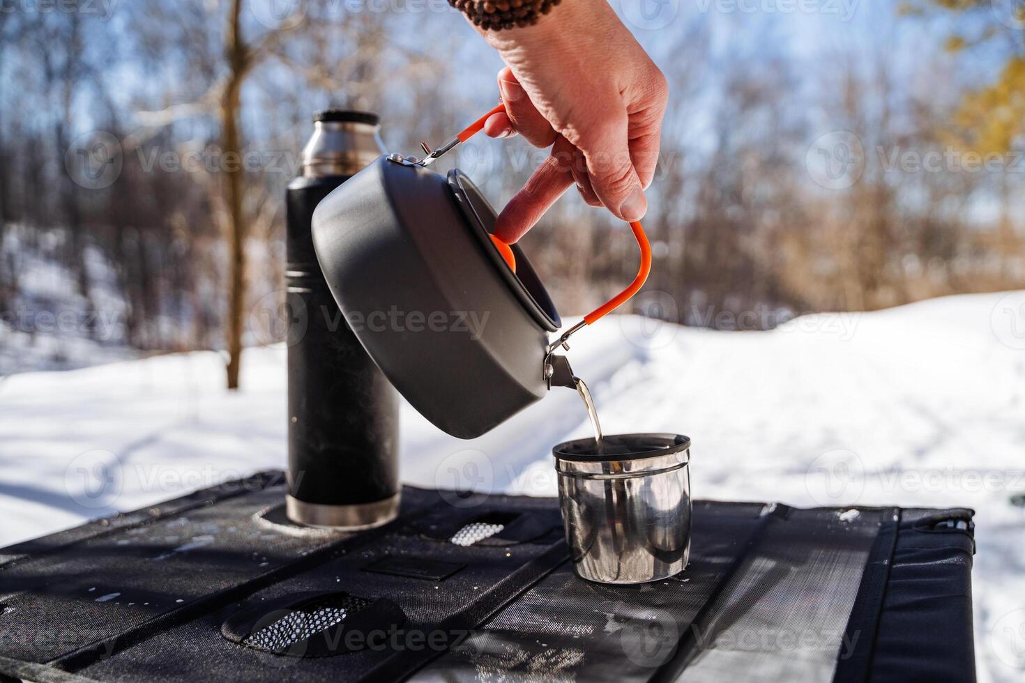 A person pours water into a cup on a camping stove photo