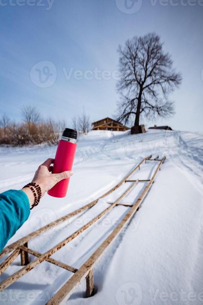 A person holding a red thermos cup in the snow photo