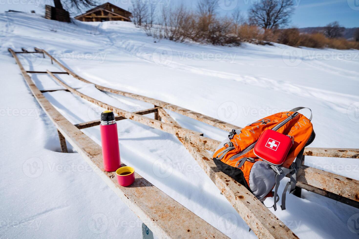 A wooden bench with a backpack and a water bottle photo