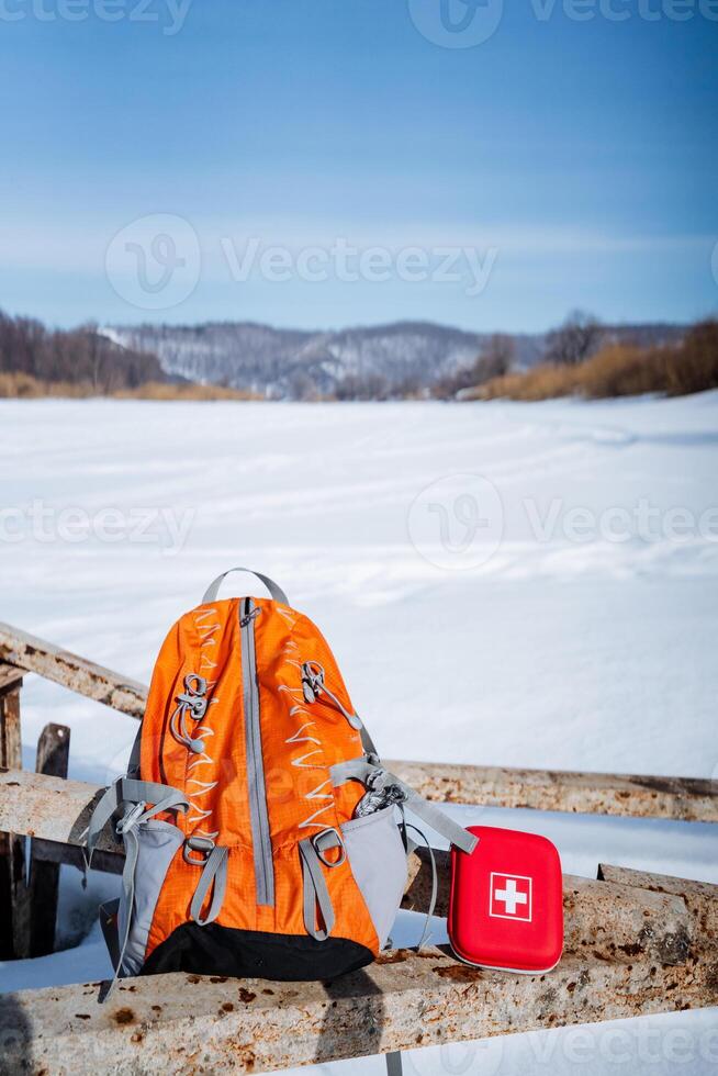 A backpack and a first aid kit on a wooden bench photo