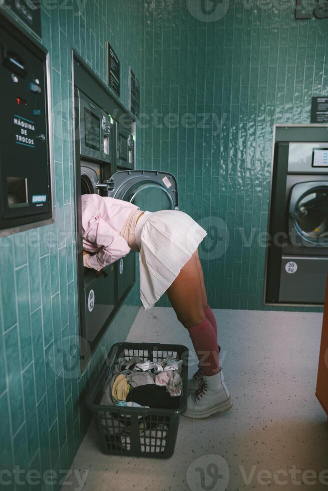 A Young Adult is relaxing in the Laundry Room while handling Clothes and doing chores photo