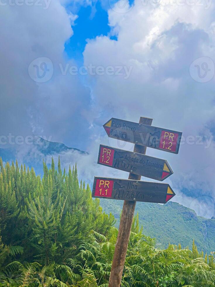 Madeira island PR1 Pico do Arieiro hiking trail sign famous place road route valley path fog mist green grass eco nature connection dramatic sky mountains challenge achievement vertical photo