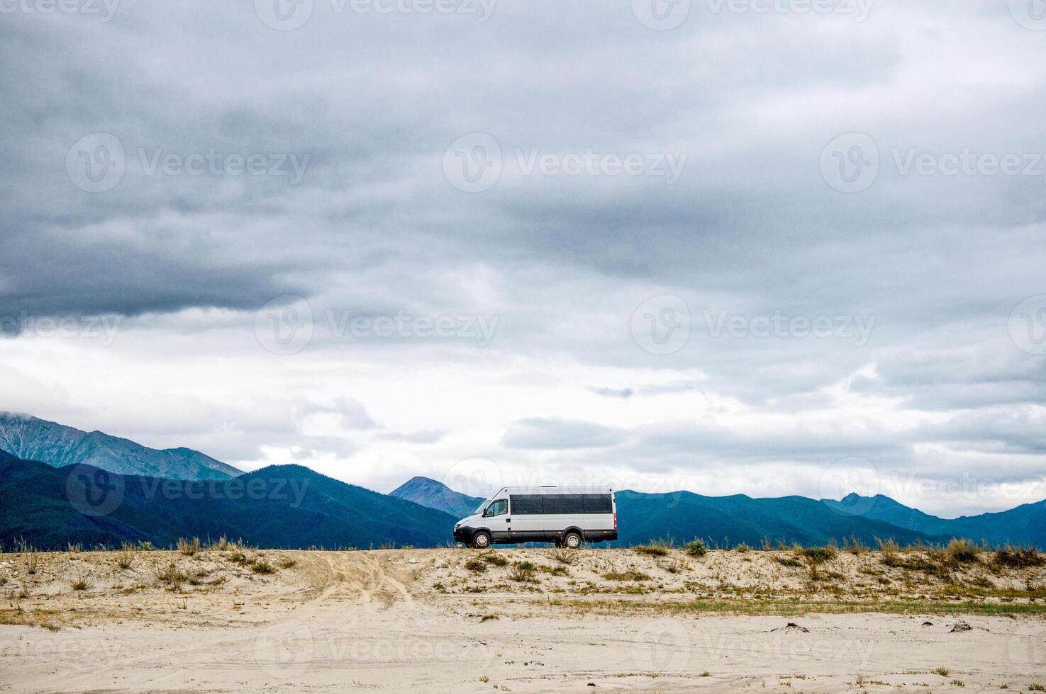 Car with nice tourists is driving along country road among mountains photo