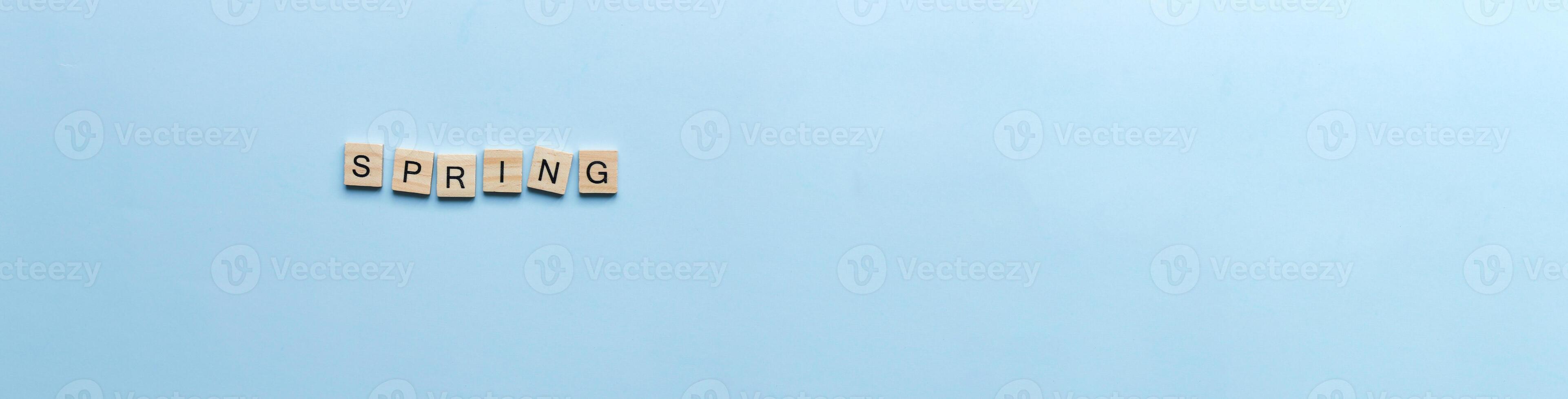 Banner The word spring laid out in wooden letters. Flat lay spring on blue background photo