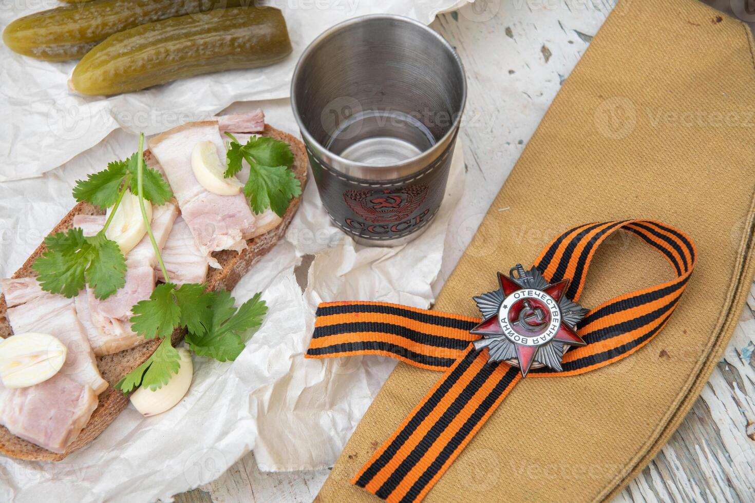 Still life with a glass of vodka with an inscription in Russian USSR and snacks, St. George's ribbon, the Order of the Great Patriotic War, the celebration of Victory Day on May 9,top view photo