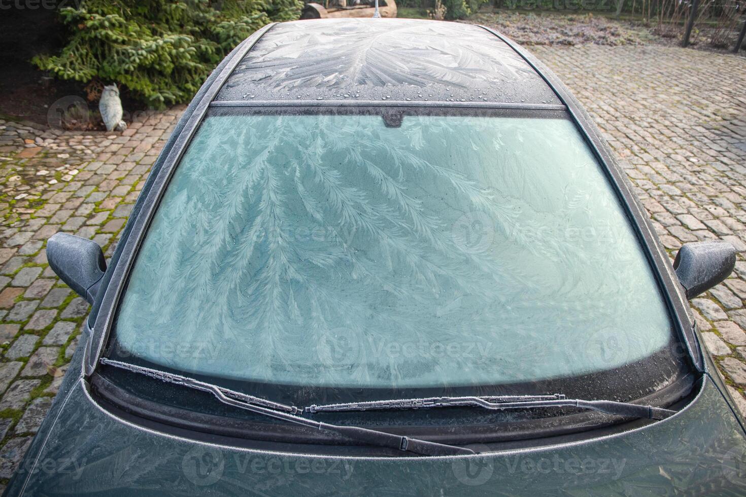 Nature drawings frost patterns on the windshield and on the roof of the car at below zero air temperature, abstract winter pattern, photo