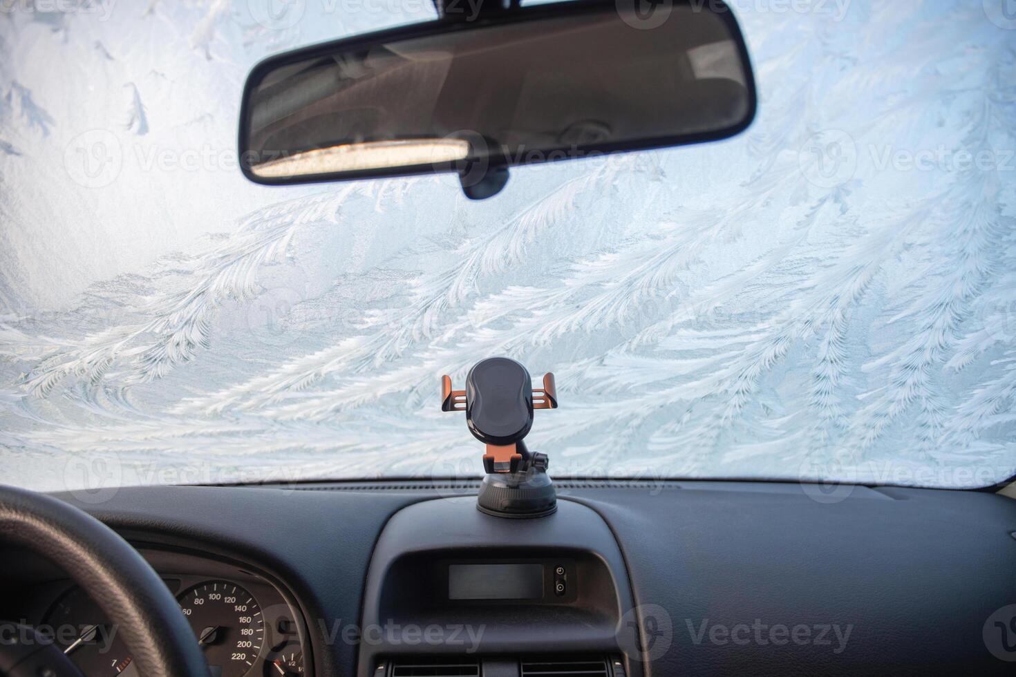 Nature drawings frost patterns on the windshield of a car at below zero air temperature, view from inside the car on an abstract winter pattern, photo