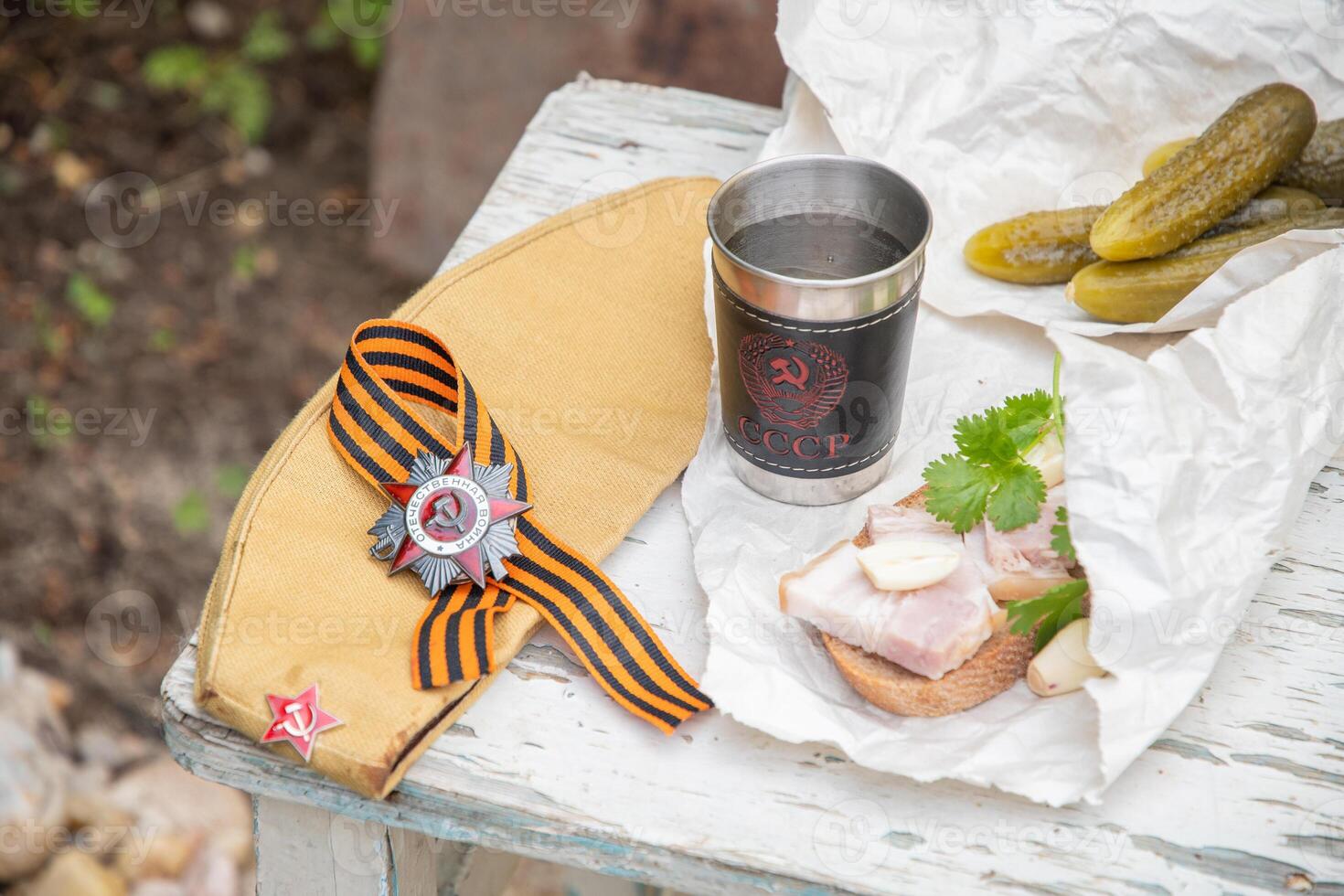 Still life on shabby chair with a glass of vodka with an inscription in Russian USSR and snacks, St. George's ribbon, Order of the Great Patriotic War, the celebration of Victory Day on May 9, photo