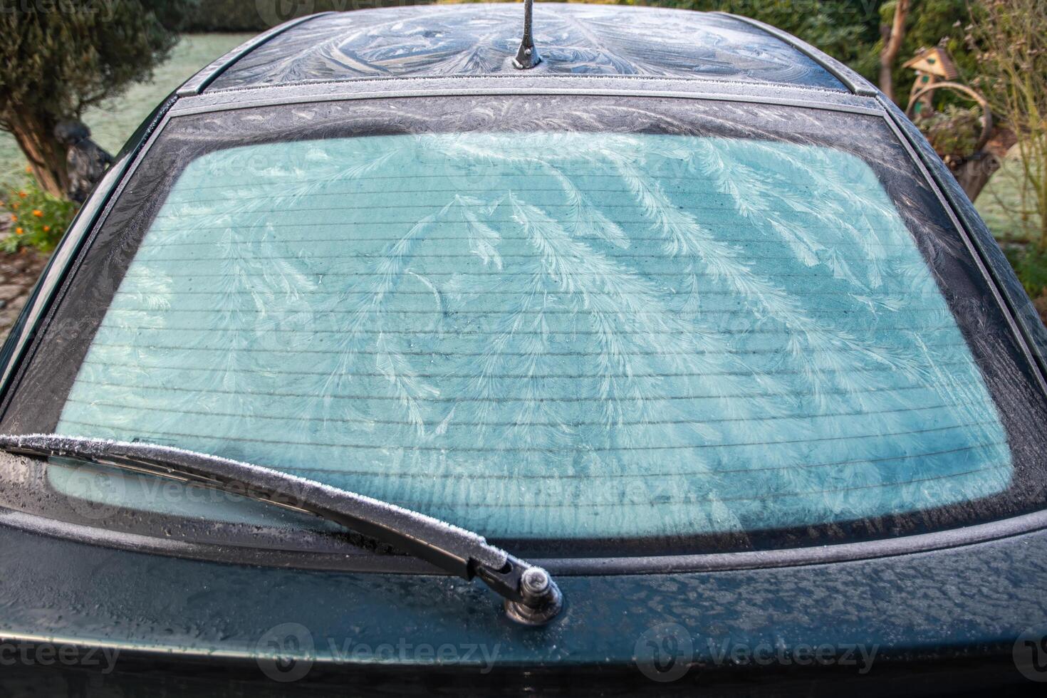 Nature draws frost patterns on glass when air temperature is below zero, abstract winter pattern on rear window of car, photo