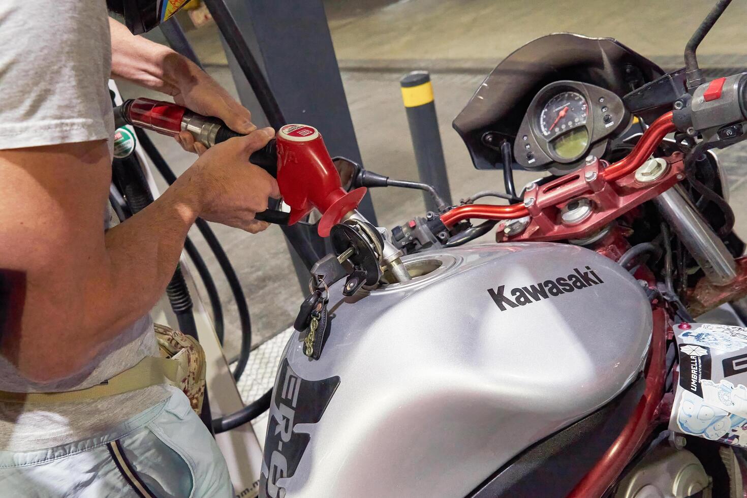 Zabbar, Malta - 01.07.2024. Kawasaki motorcycle being refueled at gas station. Close up of biker full-up Motorcycle tank during travel maintenance. Motorcycle is refueling process concept photo