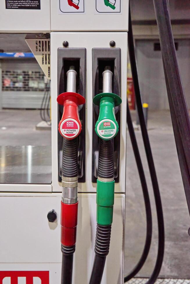 Zabbar, Malta -01.07.2024. Close up of red and green fuel pump nozzles labeled for power and unleaded gasoline at a modern gas station with a clean industrial background photo