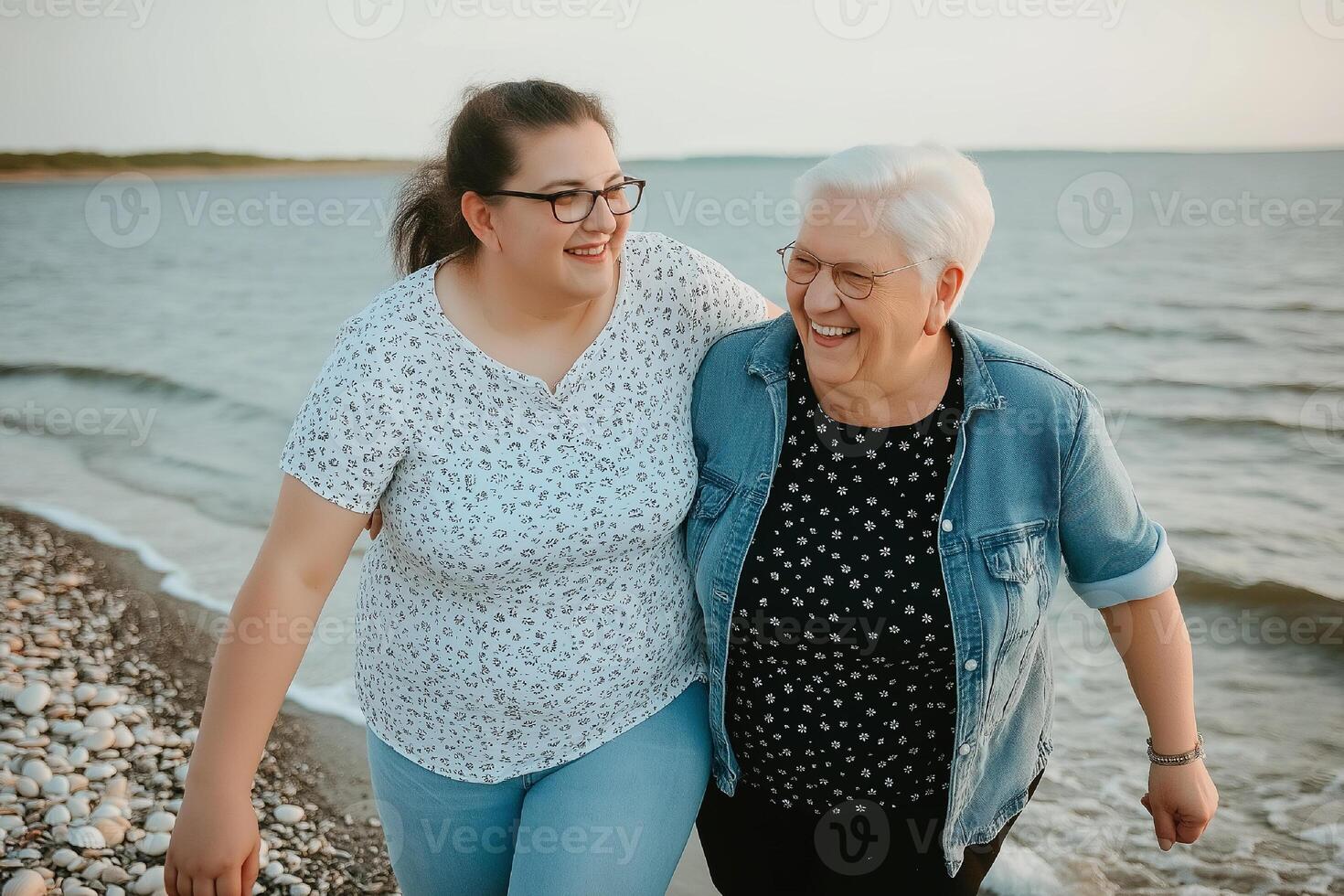 Joyful bonding moment between grandmother and granddaughter walking on pebbled beach. mothers Day photo