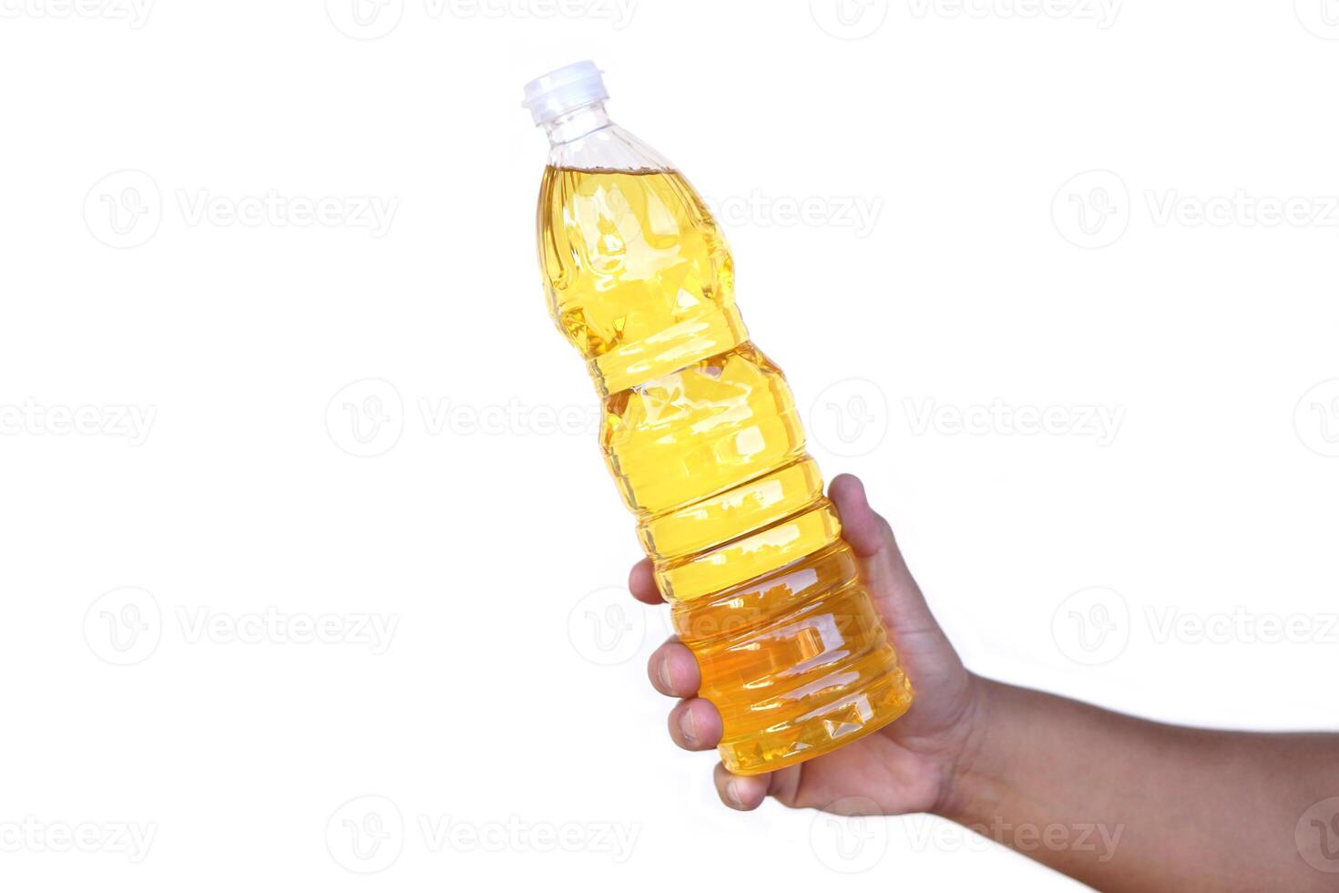 Hand holds bottle of cooking oil, isolated on white background. Extracted from seeds or from other parts of plants, such as sunflower seeds, soy beans, olive, palm fruits. photo