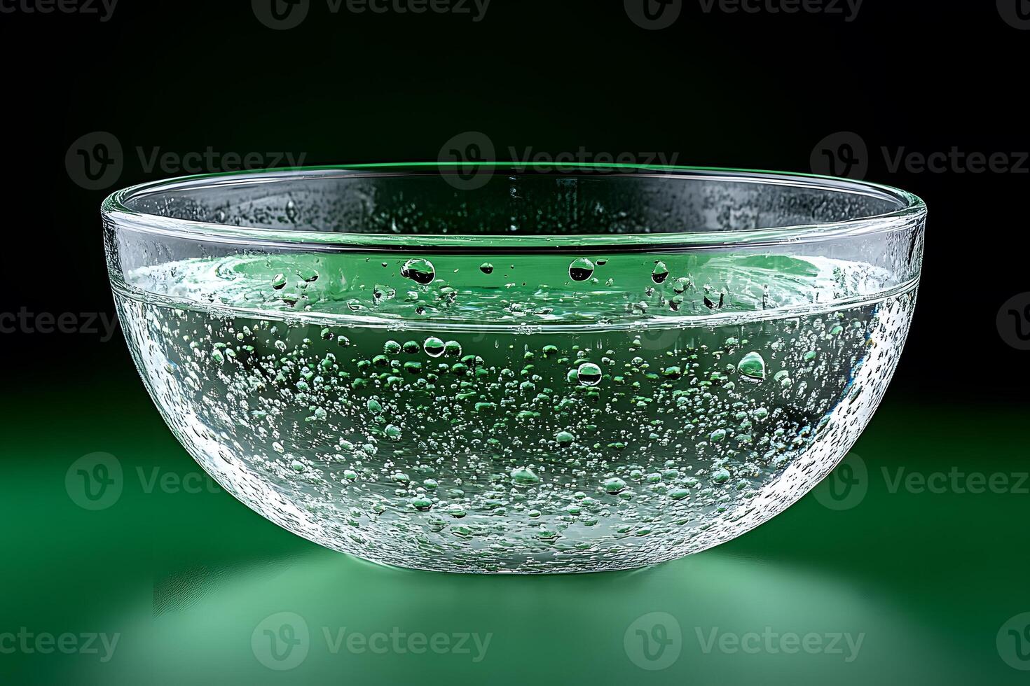 Close-Up of Transparent Bowl Filled with Sparkling Water on Green Background photo