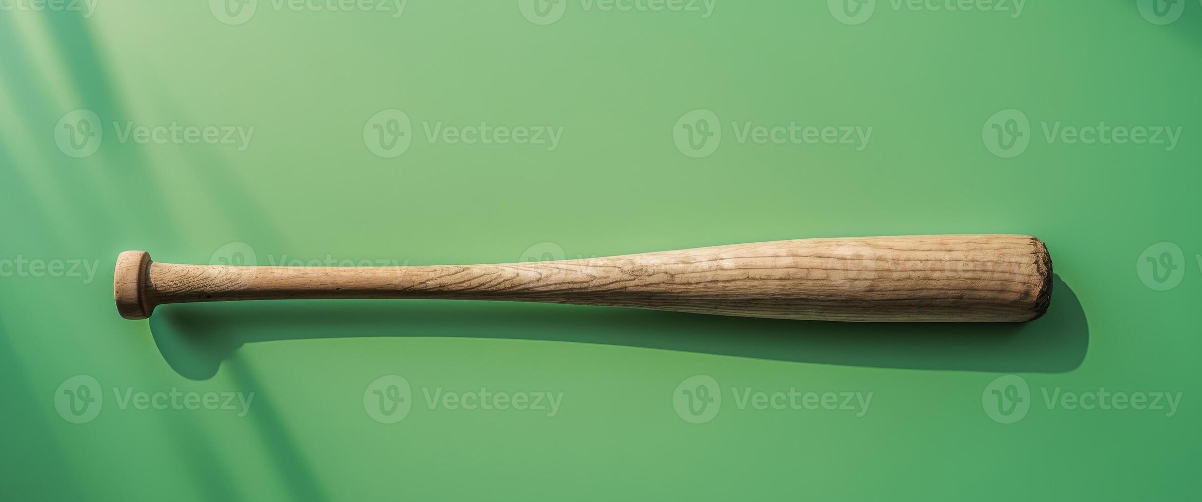 A wooden baseball bat with a green background. photo