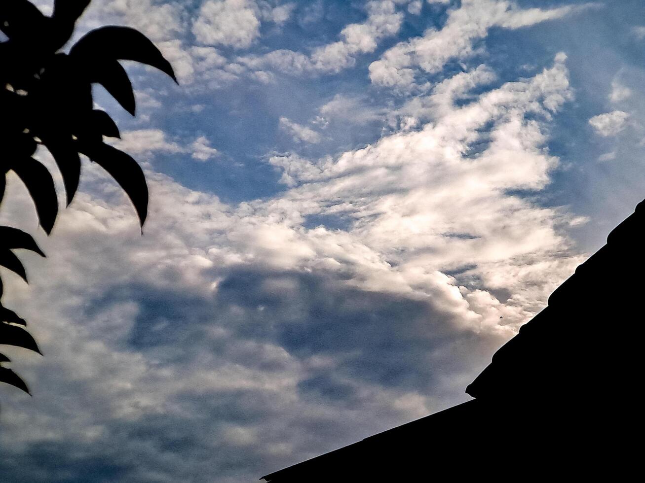 A silhouette of a building and a sky with clouds photo