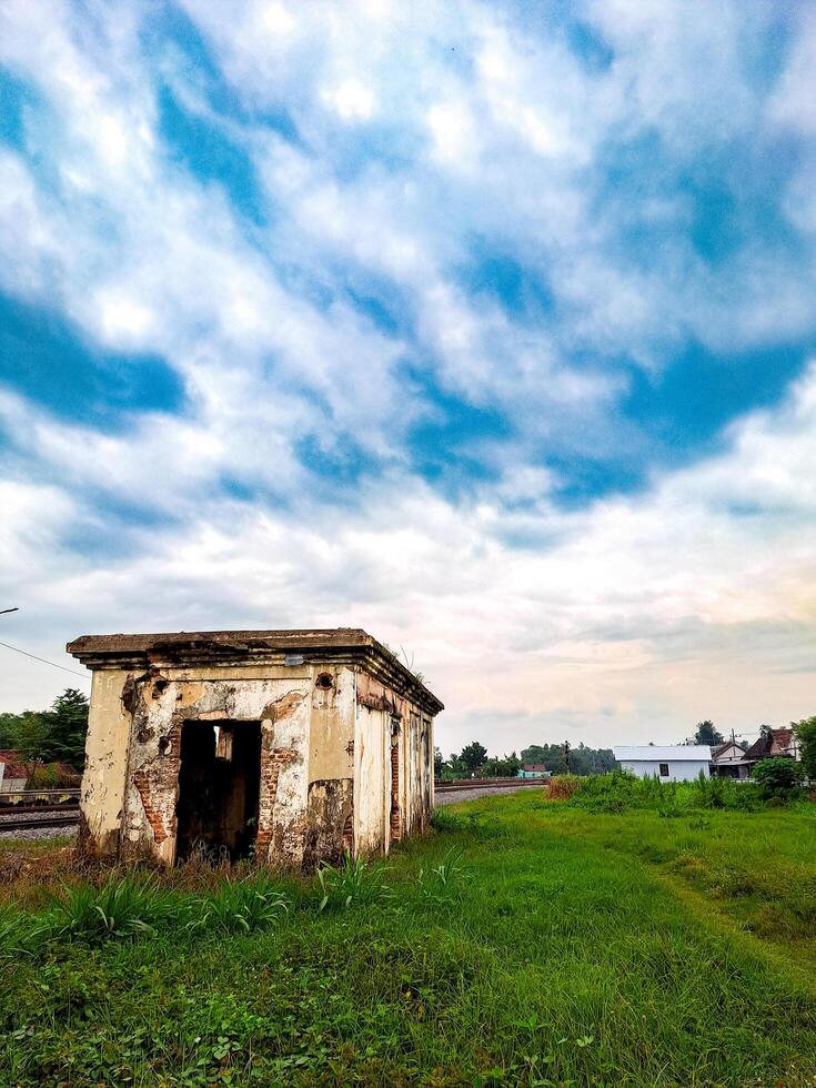 An old abandoned building sits in the middle of a grassy field photo