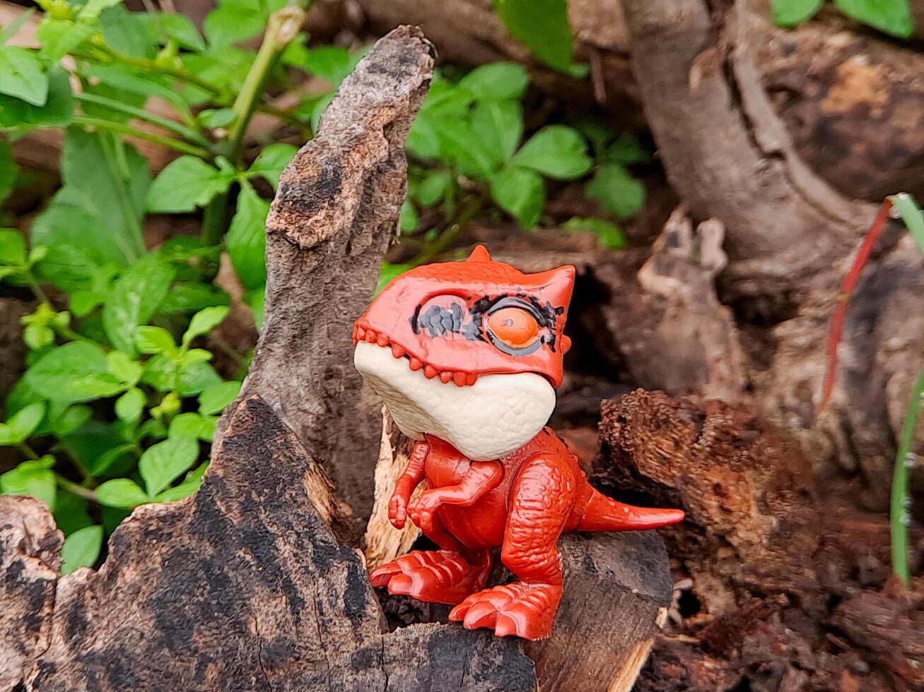 A toy dinosaur is sitting on a log photo