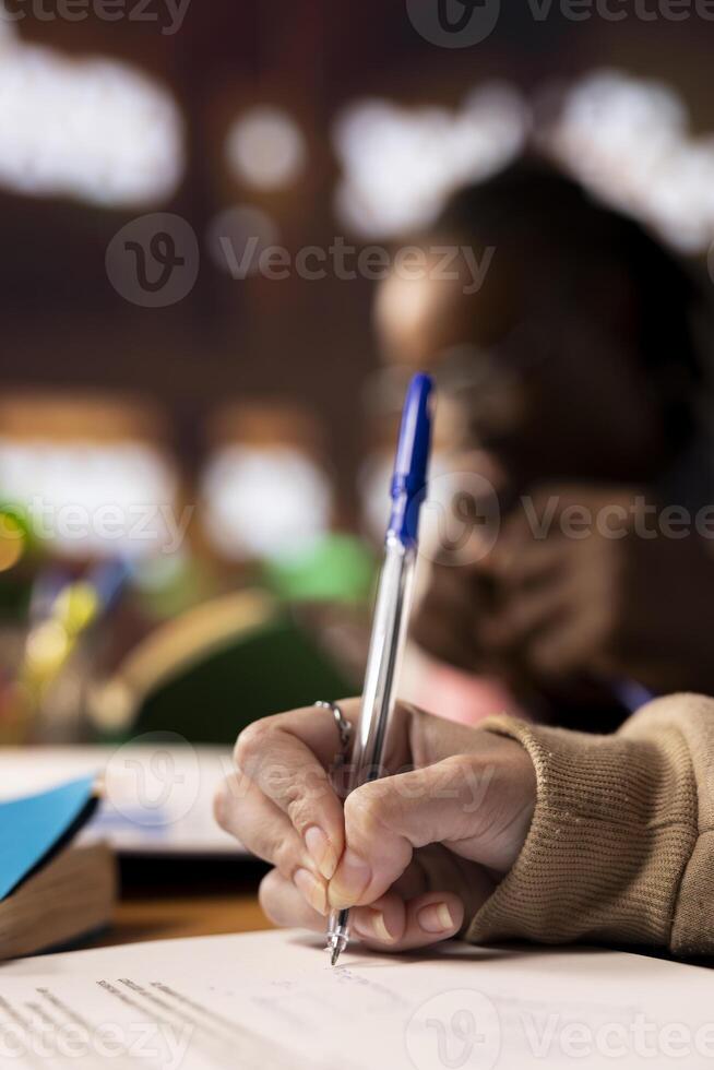 Students at the library engaging in a group discussion about business management and taking notes for their team project, doing research by consulting university database. Student life. Close up. photo