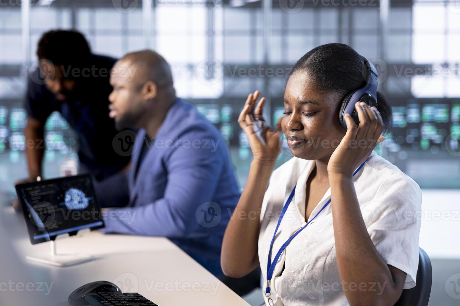 Engineer in data center listening songs while using system monitoring software on computers to identify errors. Woman wearing headphones, enjoying music in server farm, repairing infrastructure photo