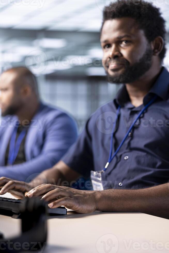 Cybersecurity division staff member monitoring security incidents affecting server hub network. African american developer in data center protecting company critical infrastructure from cyber threats photo