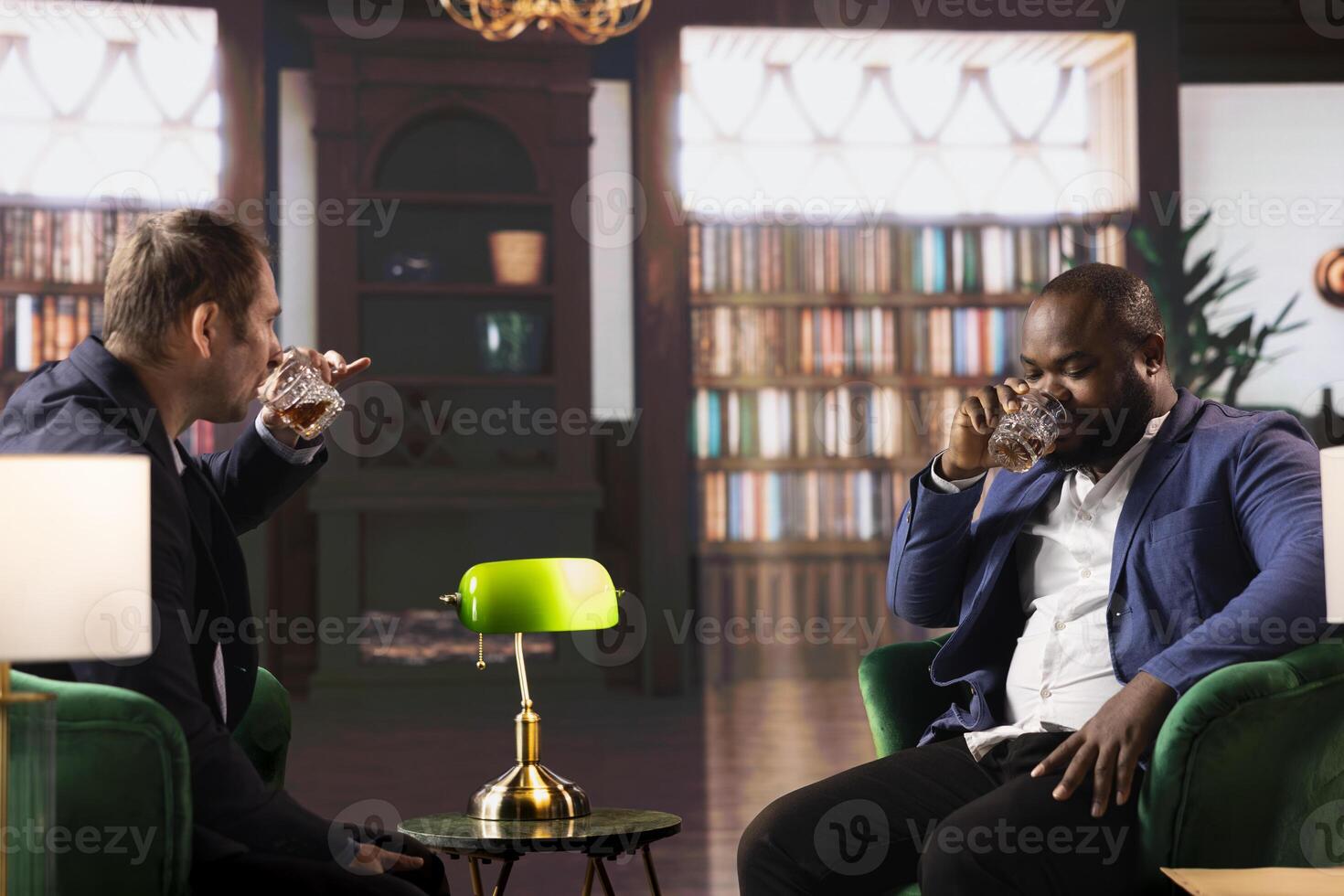 Two multiethnic businessmen sharing a whiskey in an elegant library, discussing business strategy and building trust. Confident gentlemen embodying luxury and elite social culture. photo