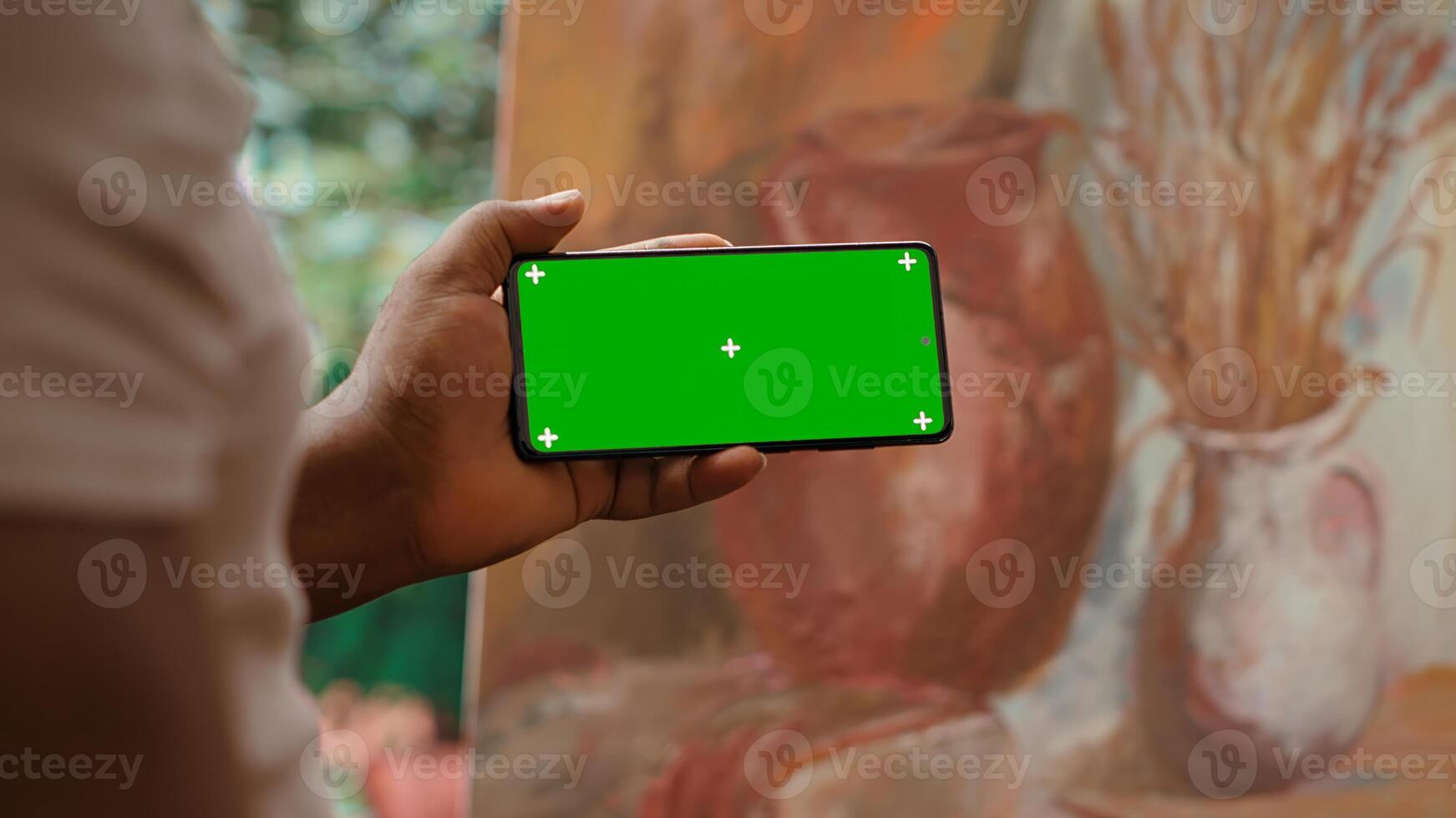 African american painter using a gadget with copy space screen in workshop, working on his new nature inspired masterpiece on canvas. Using watercolor paint and creativity in atelier. Camera A. photo